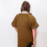 Person wearing a brown dress with white trim against a white background