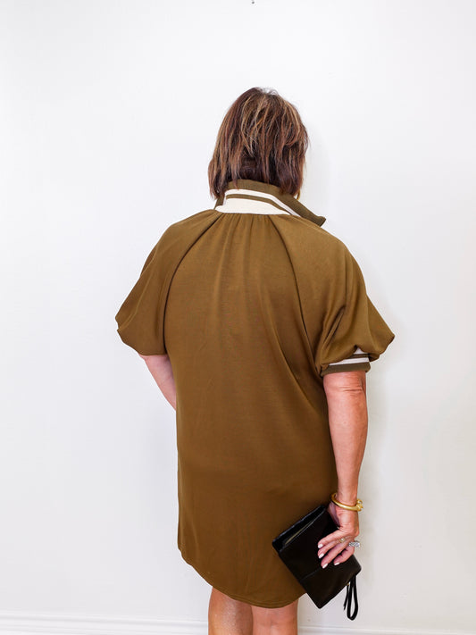Person wearing a brown dress with white trim against a white background