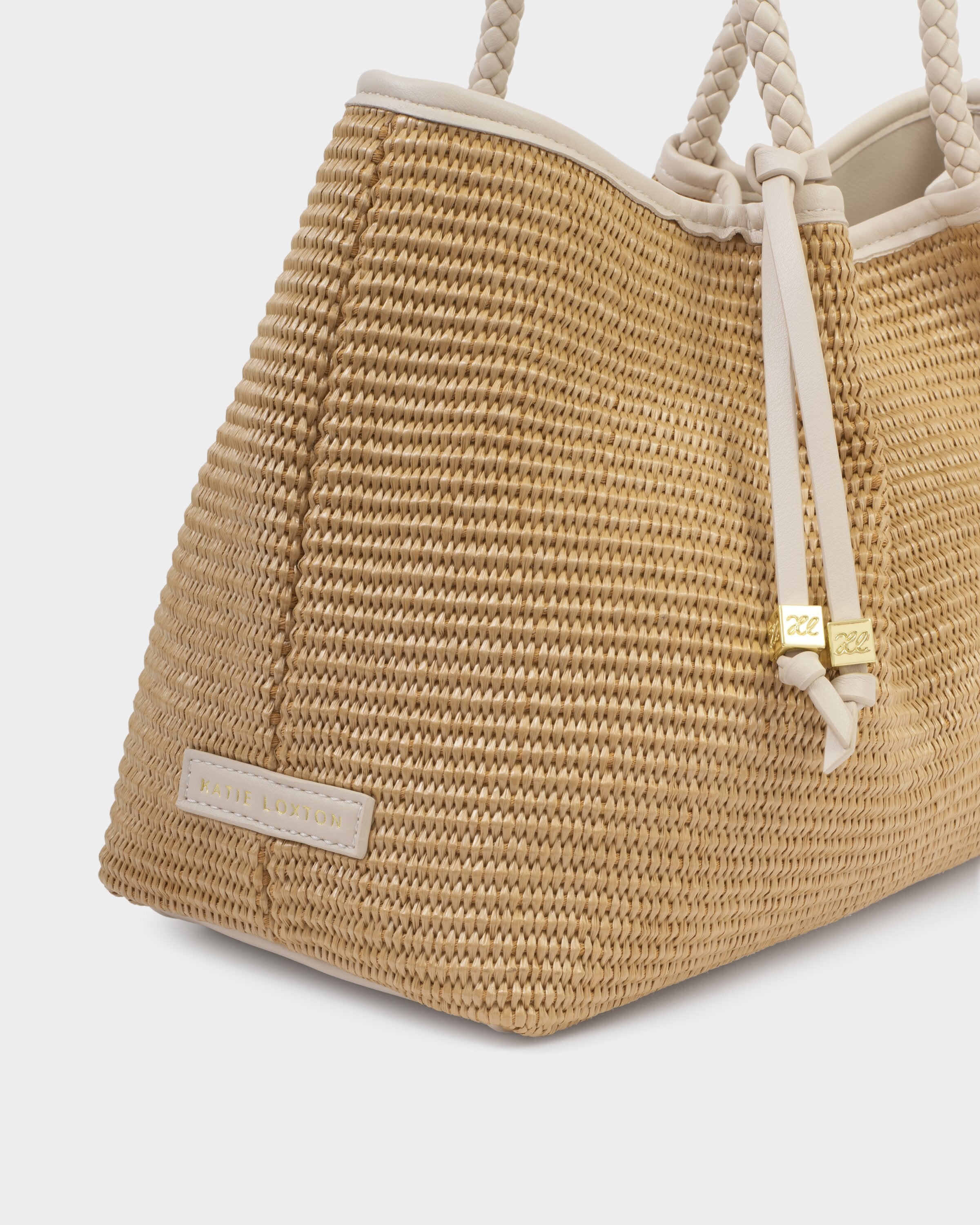 Woven straw bag with rope handles on a light gray background
