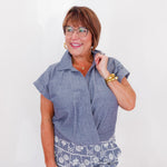 Woman wearing a blue shirt and patterned pants against a white background