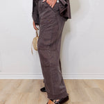 Person wearing brown cargo pants standing against a white wall.