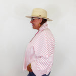 Person wearing a red and white striped shirt, blue jeans, and a beige hat against a white background