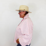 Person wearing a red and white striped shirt, blue jeans, and a beige hat against a white background