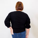Person wearing a black top and blue jeans against a white background