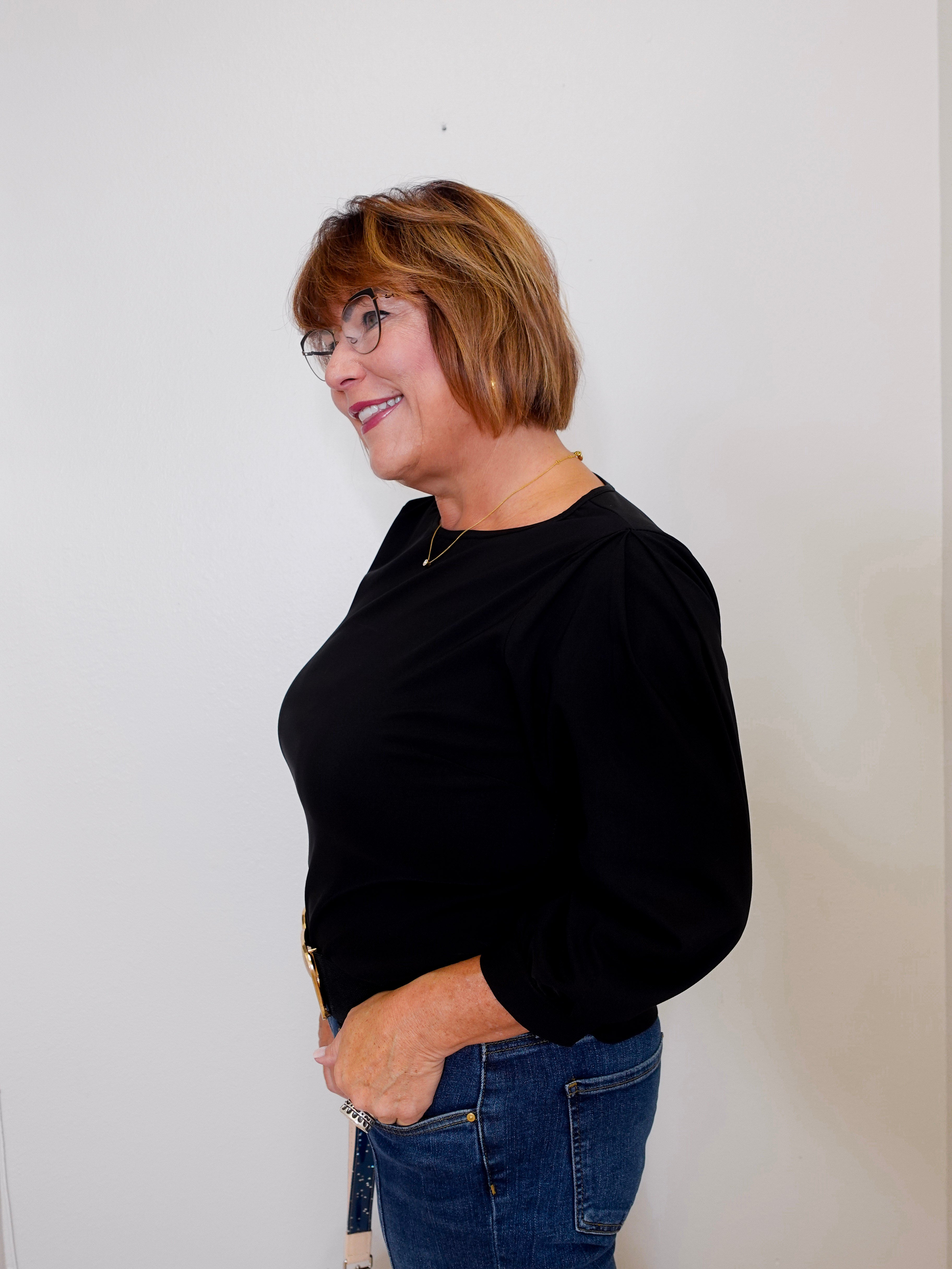 Woman wearing a black top and blue jeans against a white background