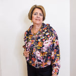 Woman wearing a floral jacket against a white wall