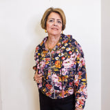 Woman wearing a floral jacket against a white wall