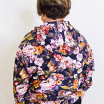 Woman wearing an apny floral print hooded jacket. 