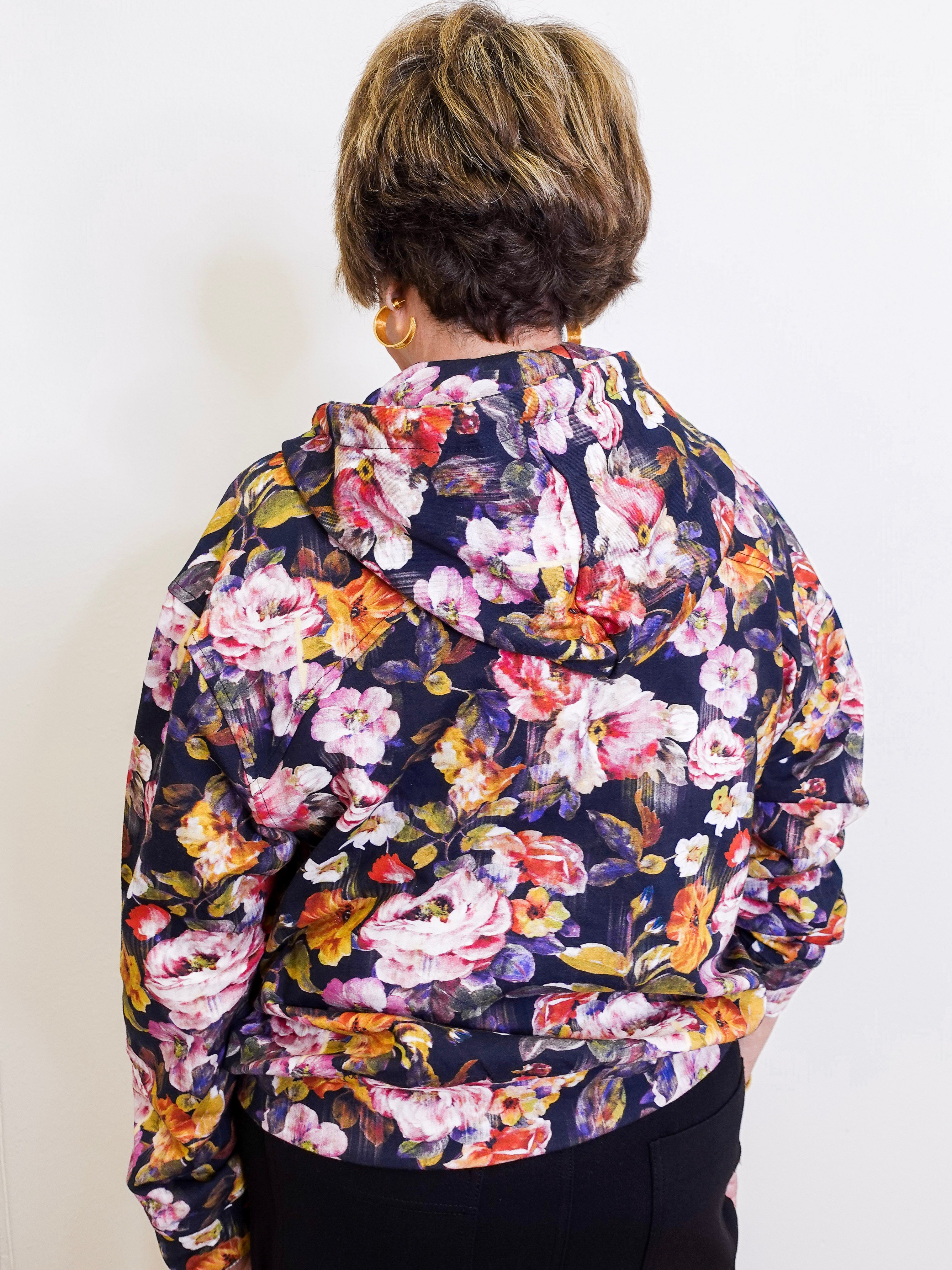 Woman wearing an apny floral print hooded jacket. 