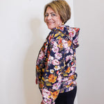 Woman wearing a floral print hooded zip front jacket from Apny in front. white background. 