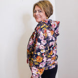 Woman wearing a floral print hooded zip front jacket from Apny in front. white background. 