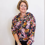 Woman wearing a floral print zip front hooded jacket. 