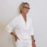 Woman wearing a white outfit against a plain background