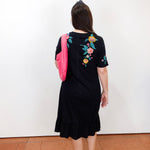 Woman modeling a Zivana ruffle knit midi dress featuring a black knit fabric, vibrant floral embroidery, short sleeves, and a ruffled hem.