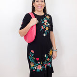 Model wearing the Zivana ruffle knit midi dress in black with colorful floral embroidery and ruffled hem.